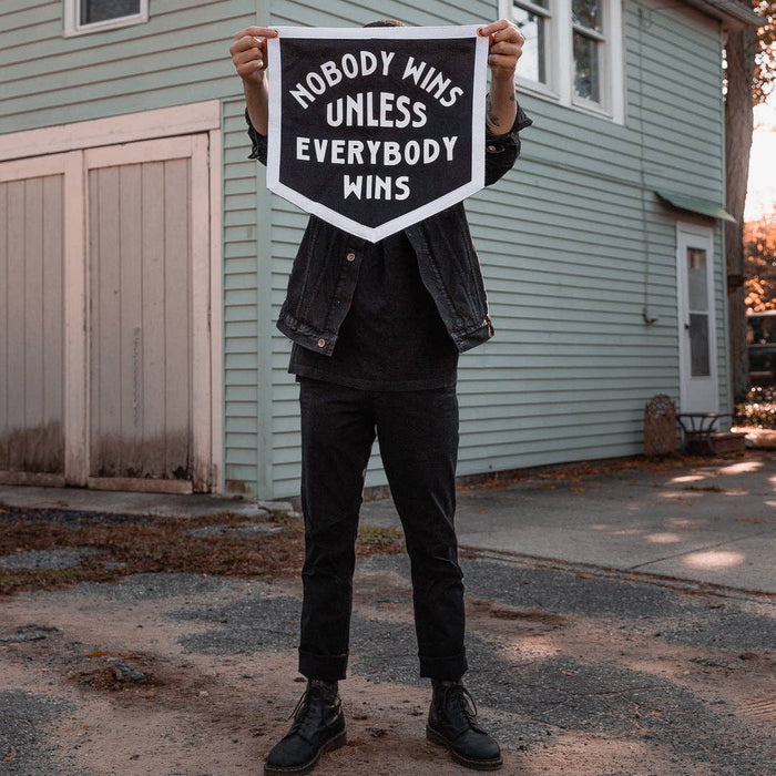 Person holding a sign with motivational text in front of a house.